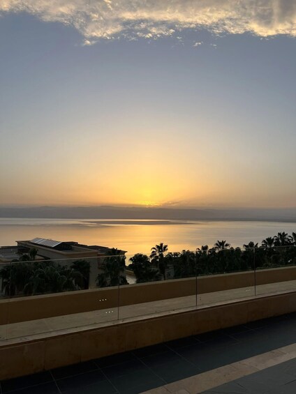 A sunset over a calm body of water with buildings and palm trees in the foreground. 3