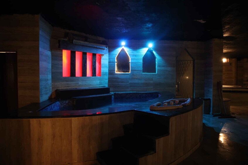 A wooden spa with a hot tub and a stone wall with illuminated windows. 5