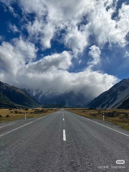 A road leading through a mountainous landscape with a clear sky and clouds. 3