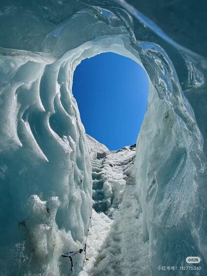 An ice cave with a clear blue sky visible through the entrance. 4
