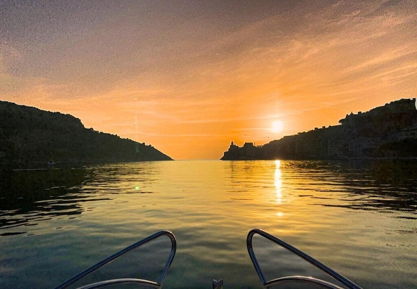 A sunset over calm water with hills on either side. 4