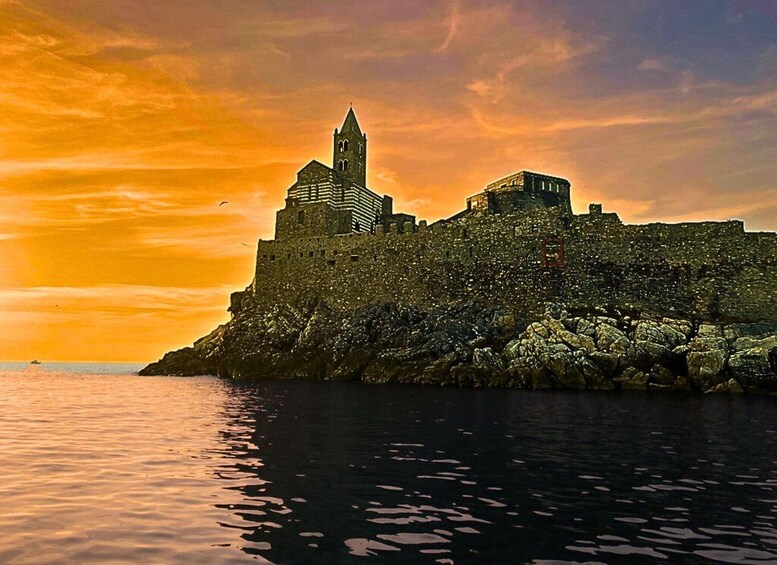 A historic castle on a rocky coastline with a sunset sky. 2