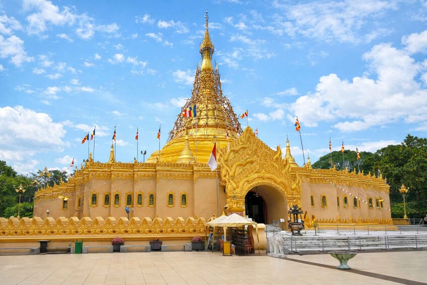 A golden temple with a spire, surrounded by flags and a clear blue sky. 4
