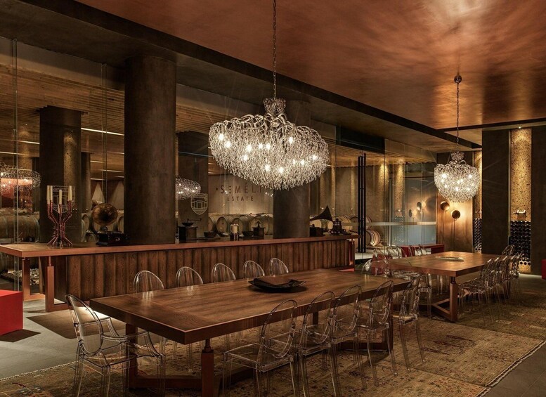 A modern dining area with wooden tables, clear chairs, and ornate chandeliers. 3