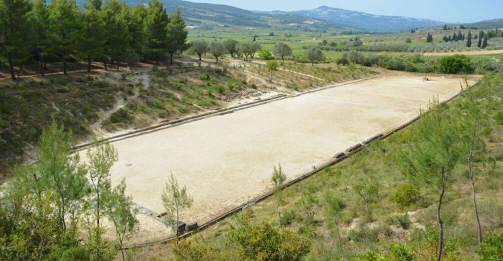 A large open field with a dirt path and sparse vegetation. 4