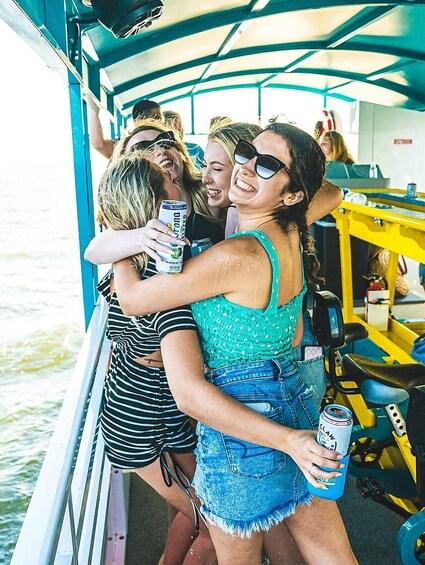 People on a boat, holding drinks, with a water body in the background. 2