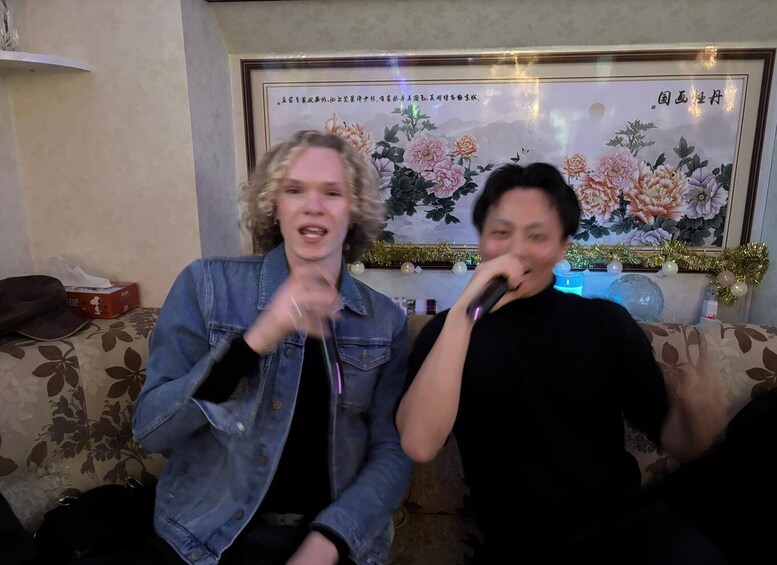 Two people sitting on a couch with a floral painting and a Christmas tree in the background. 2