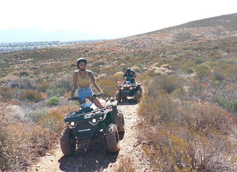 Two people on ATVs on a dirt trail in a desert landscape. 3