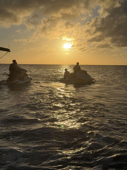 Two people on jet skis in the ocean during sunset. 2