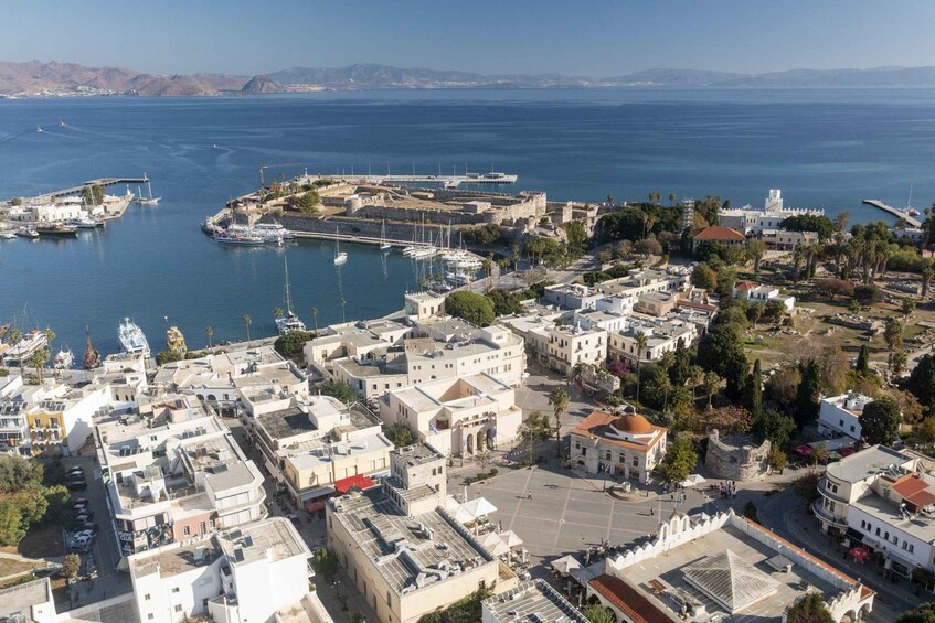 A coastal town with historic buildings, a marina, and a fort overlooking the sea. 3