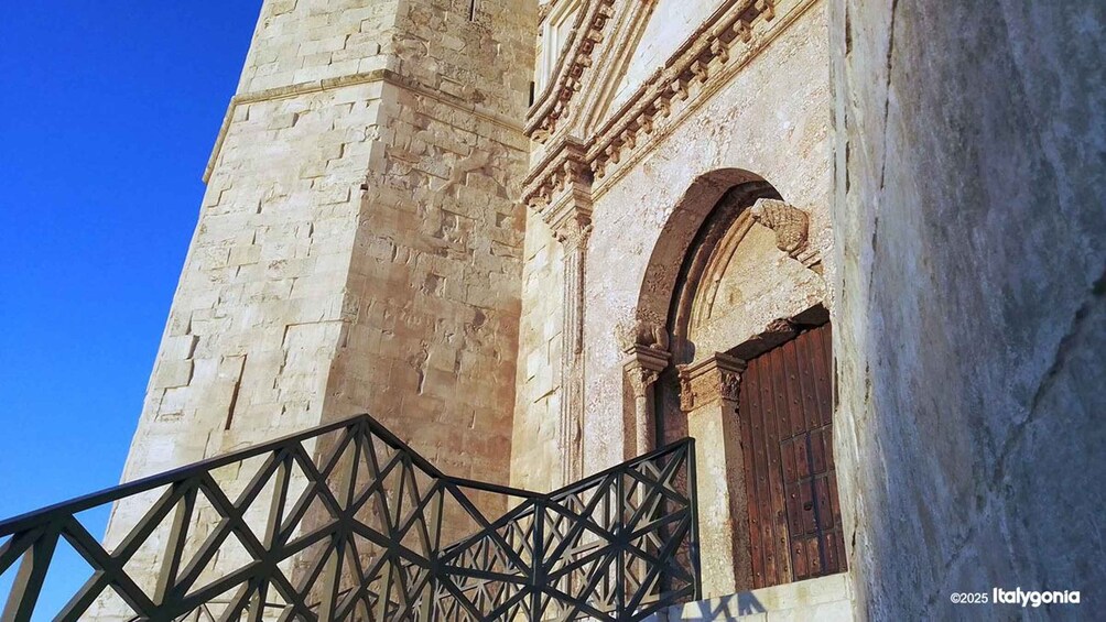 A stone building with an arched doorway and a metal railing. 3