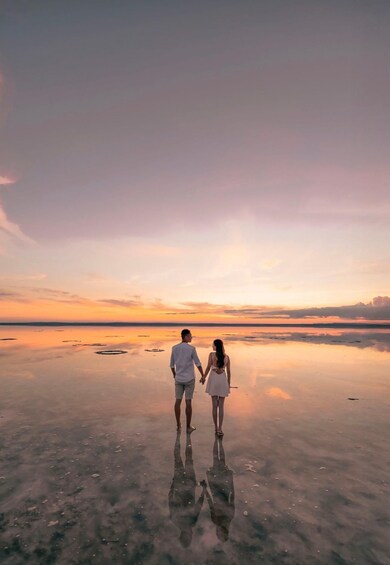 A couple walking on a reflective water surface at sunset. 1