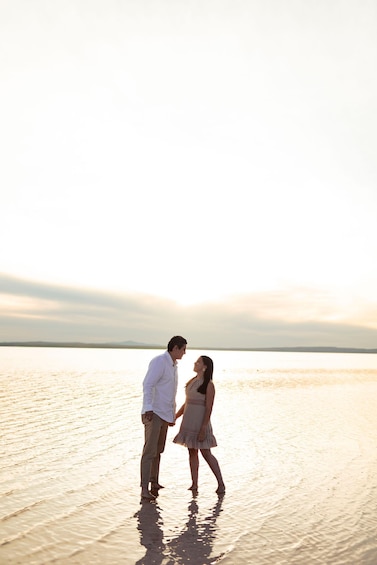 A couple standing on a beach during sunset. 5