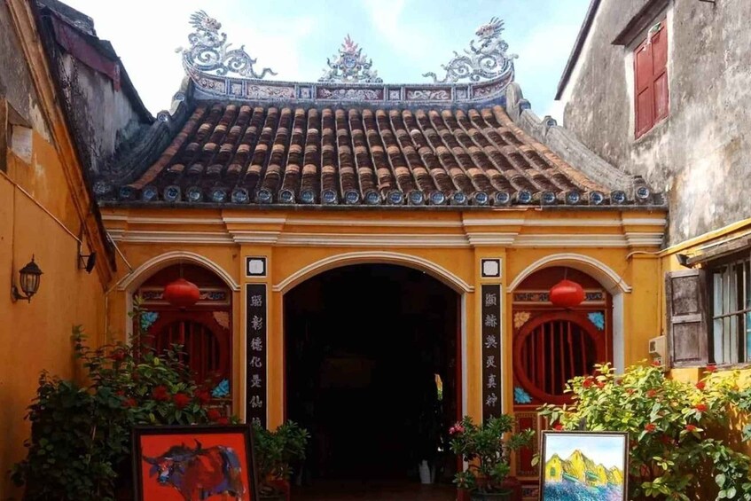 A traditional building with ornate roof tiles, a red door, and potted plants. 5
