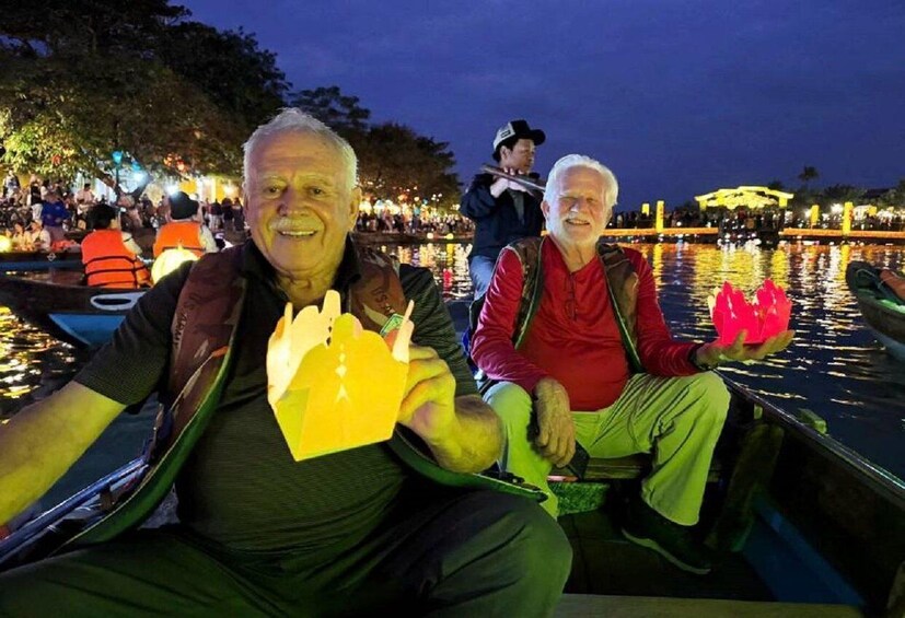 Two people on a boat with a crowd and lights in the background. 3