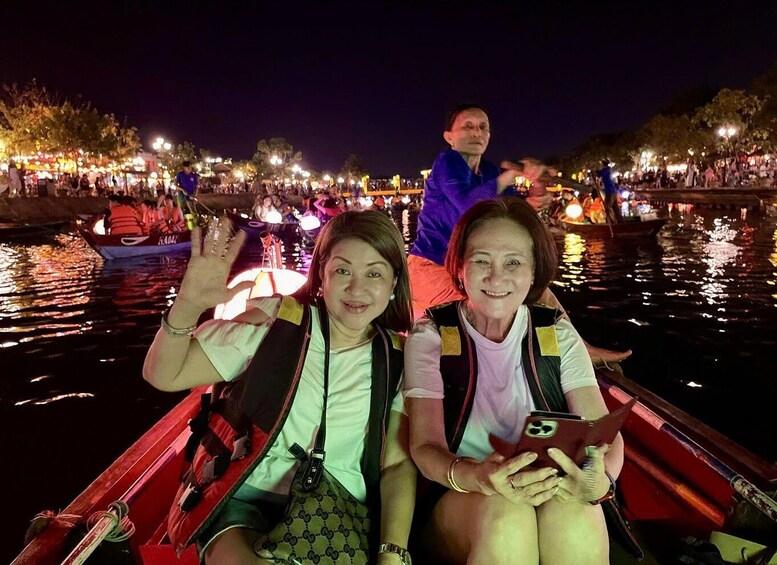 Two people on a boat with a cityscape and lights in the background. 3