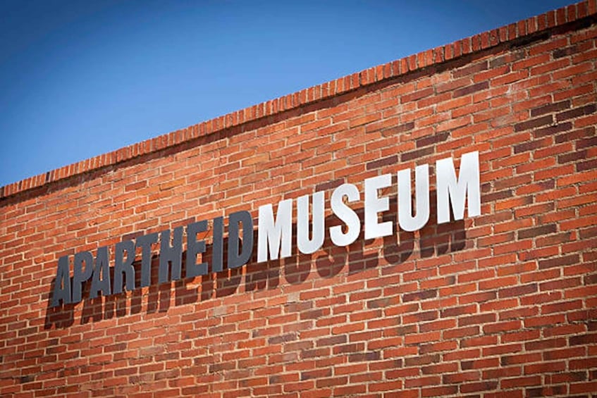 Tiiliseinä, jossa on suurilla kirjaimilla teksti: ”APARTMENTED MUSEUM”. 1