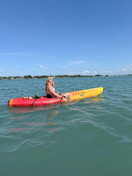 A person in a kayak on calm water with a clear sky and distant shoreline. 5