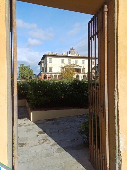 A building with a clock tower, a garden with a pathway, and a metal gate. 5