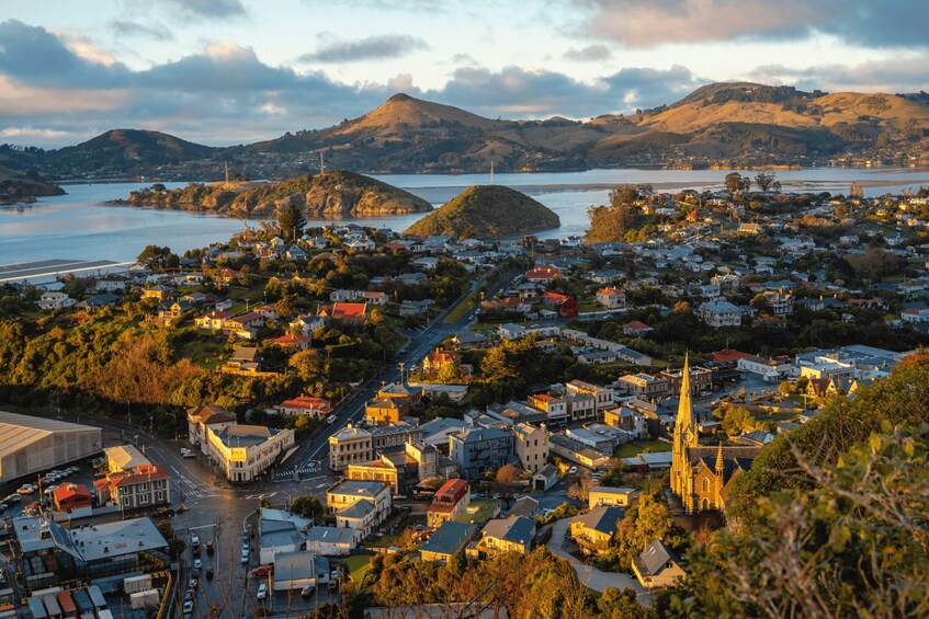 A coastal town with a prominent church spire, a bridge, and hills in the background. 3