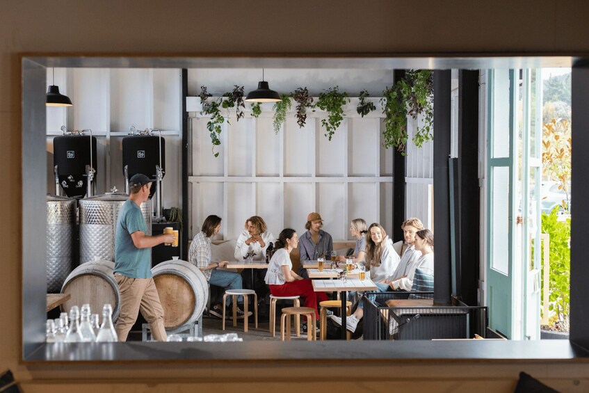 A group of people dining in a modern restaurant with wooden tables and hanging plants. 5