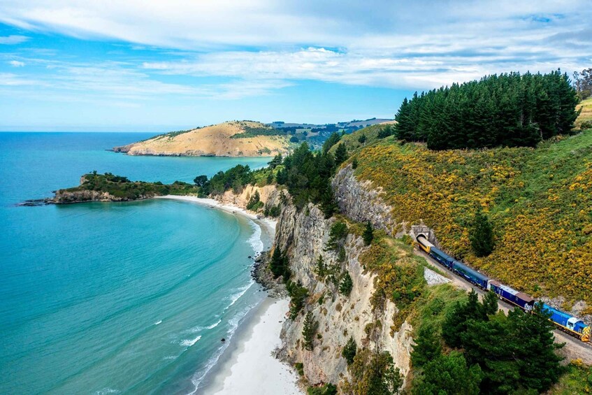 A train traveling along a coastal cliffside with a beach and ocean in the background. 4