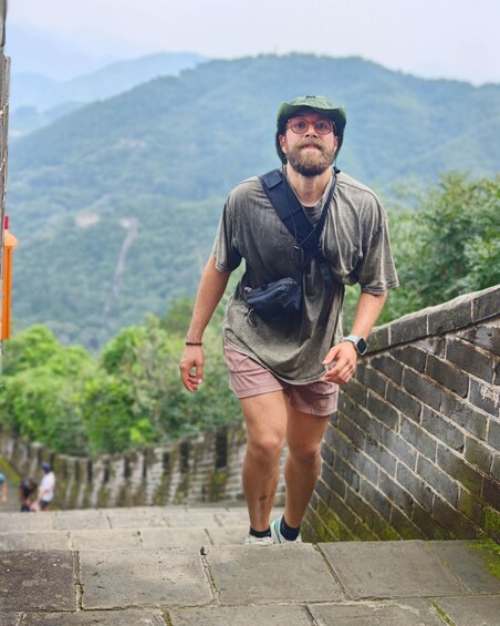 A person walking on a stone path with a green hat, a watch, and a fanny pack. 2