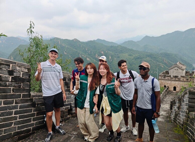 A group of people standing on the Great Wall of China with mountains in the background. 4