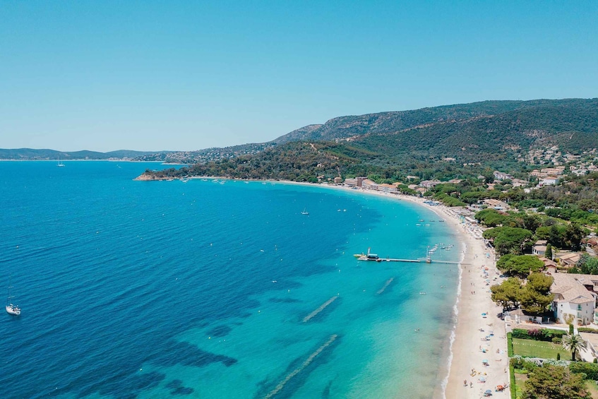 A coastal town with a beach, boats, and a mountainous backdrop. 5