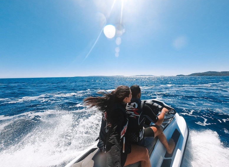 Two people on a speedboat in open water with a clear sky. 1