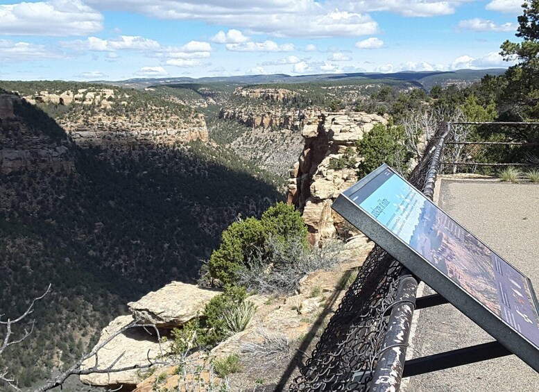 A canyon with a viewing platform and a signboard. 2