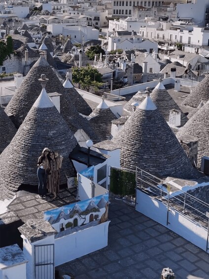 A town with distinctive conical-roofed buildings, a paved area with a white fence, and a small structure with a blue and white mural. 3