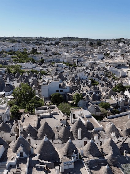 A densely packed town with numerous buildings featuring conical roofs, likely characteristic of a Mediterranean region. 1