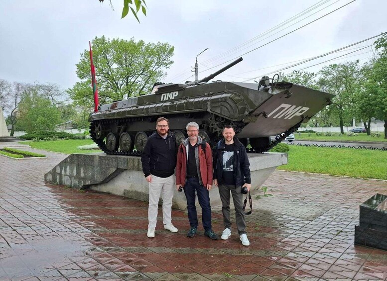 A military tank on display with three people standing in front. 5