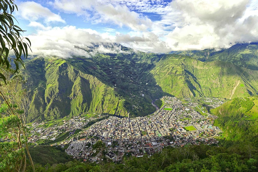A valley with a town nestled among green hills and mountains, under a partly cloudy sky. 3