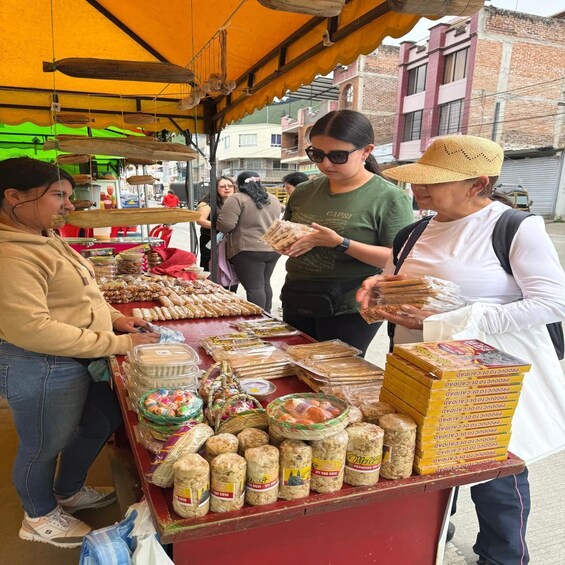 A street vendor stall with various packaged goods, including bread and snacks, under a yellow canopy. 2