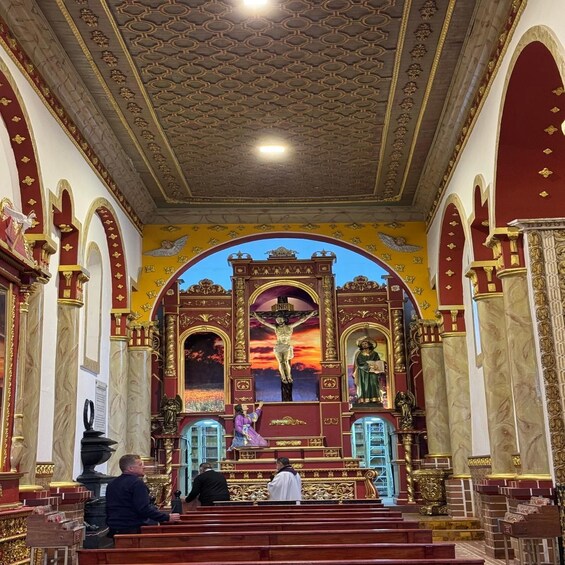 An ornate church interior with a crucifixion scene, golden arches, and a statue of a saint. 1