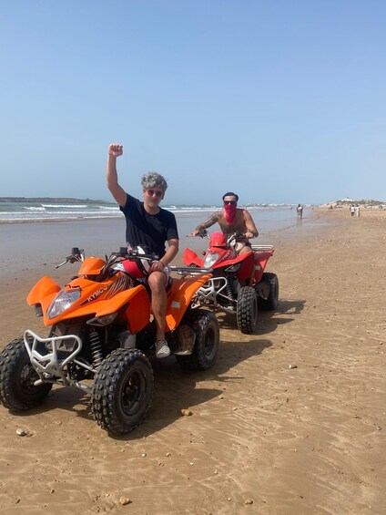 Two orange quad bikes on a sandy beach with the ocean in the background. 5