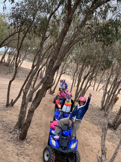 A group on a blue ATV in a tree-lined dirt path. 3