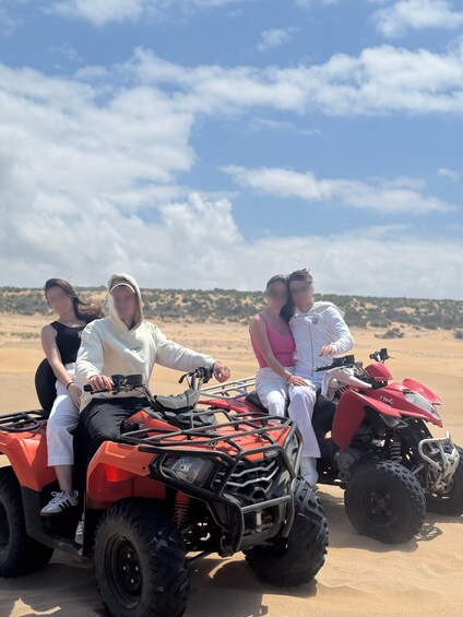Three people on an ATV in a desert landscape. 1