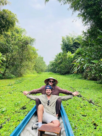 Two people in a boat on a waterway surrounded by greenery. 4