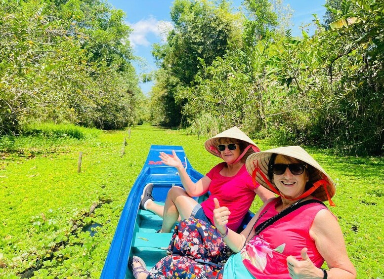 Two people in a blue boat on a river surrounded by greenery. 5