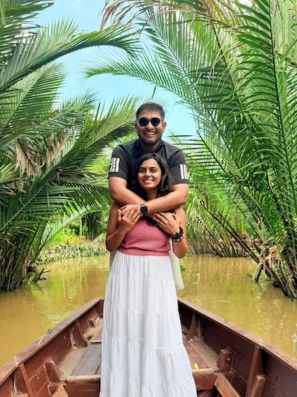 A couple embracing in a wooden boat surrounded by lush greenery and water. 1