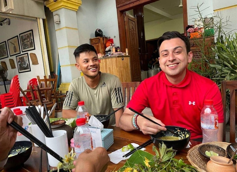 Two people dining at a table with food, chopsticks, and a bottle of water. 1