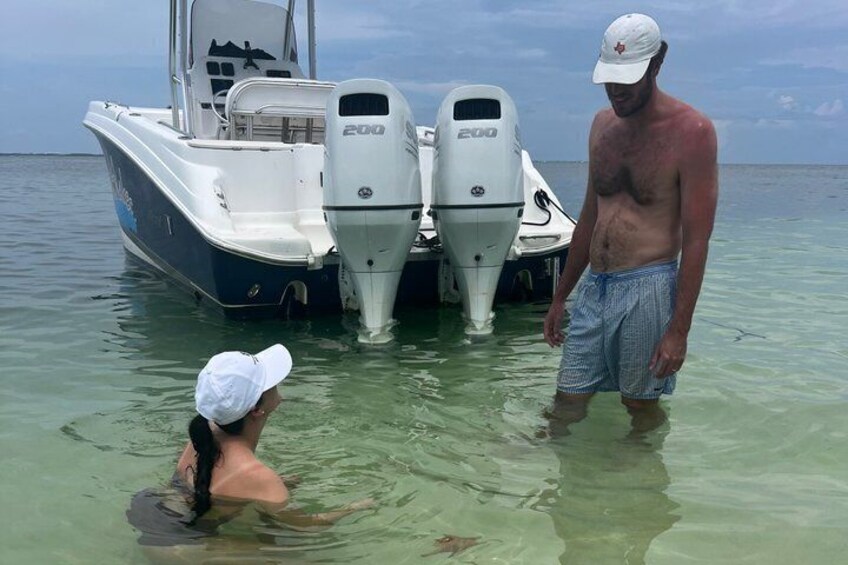 Un bateau équipé de deux moteurs hors-bord, une personne debout dans une eau peu profonde et une autre personne qui nage. 2