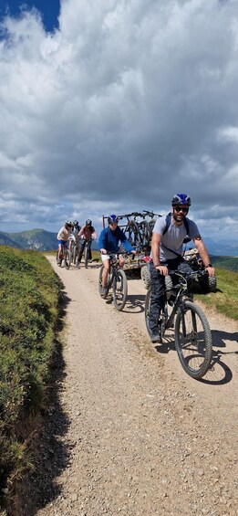 A group of cyclists on a gravel path with mountains in the background. 1