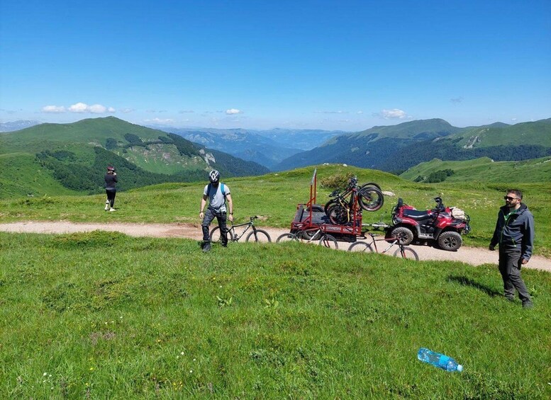 A group of people on a mountain trail with bicycles and a quad bike. 3