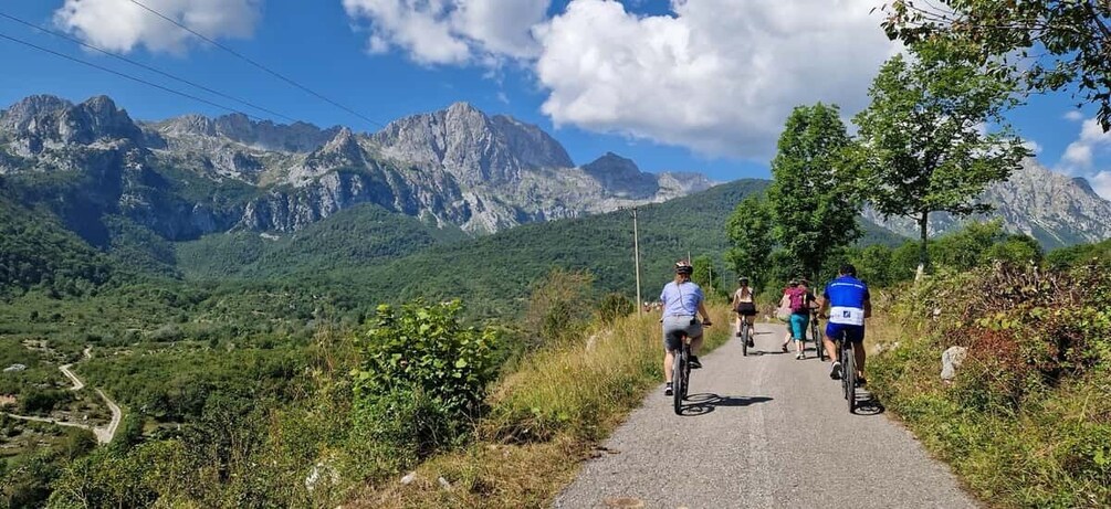 Cyclists on a mountain road with a view of rugged mountains and greenery. 5