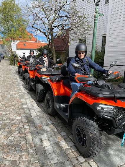 A row of orange ATVs parked on a cobblestone street. 3