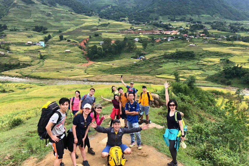 A group of hikers on a mountain trail with terraced fields in the background. 1